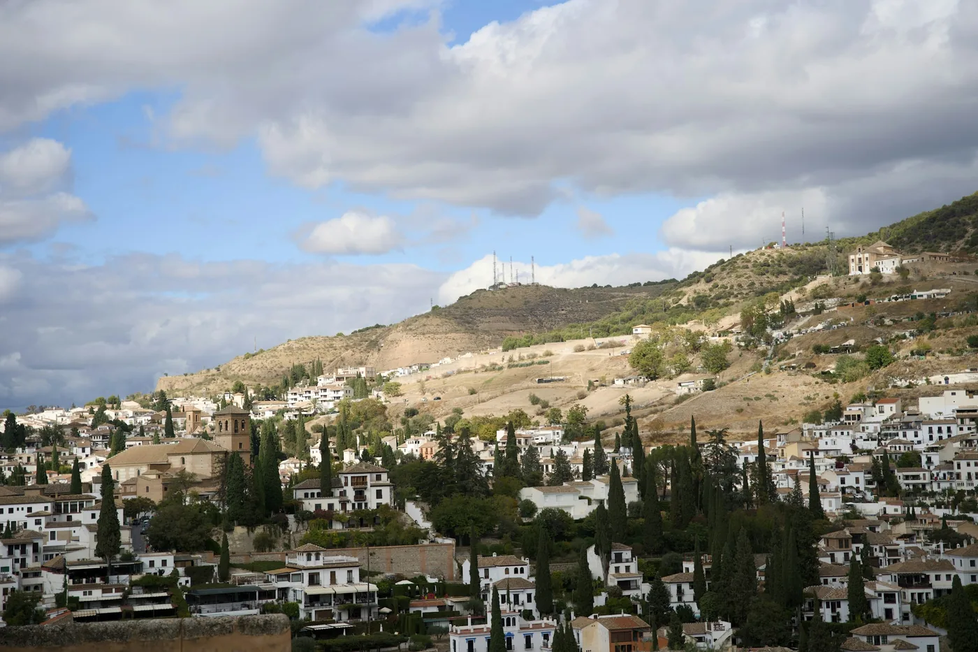 Whitewashed cave houses on the Sacromonte hillside with the Alhambra beyond